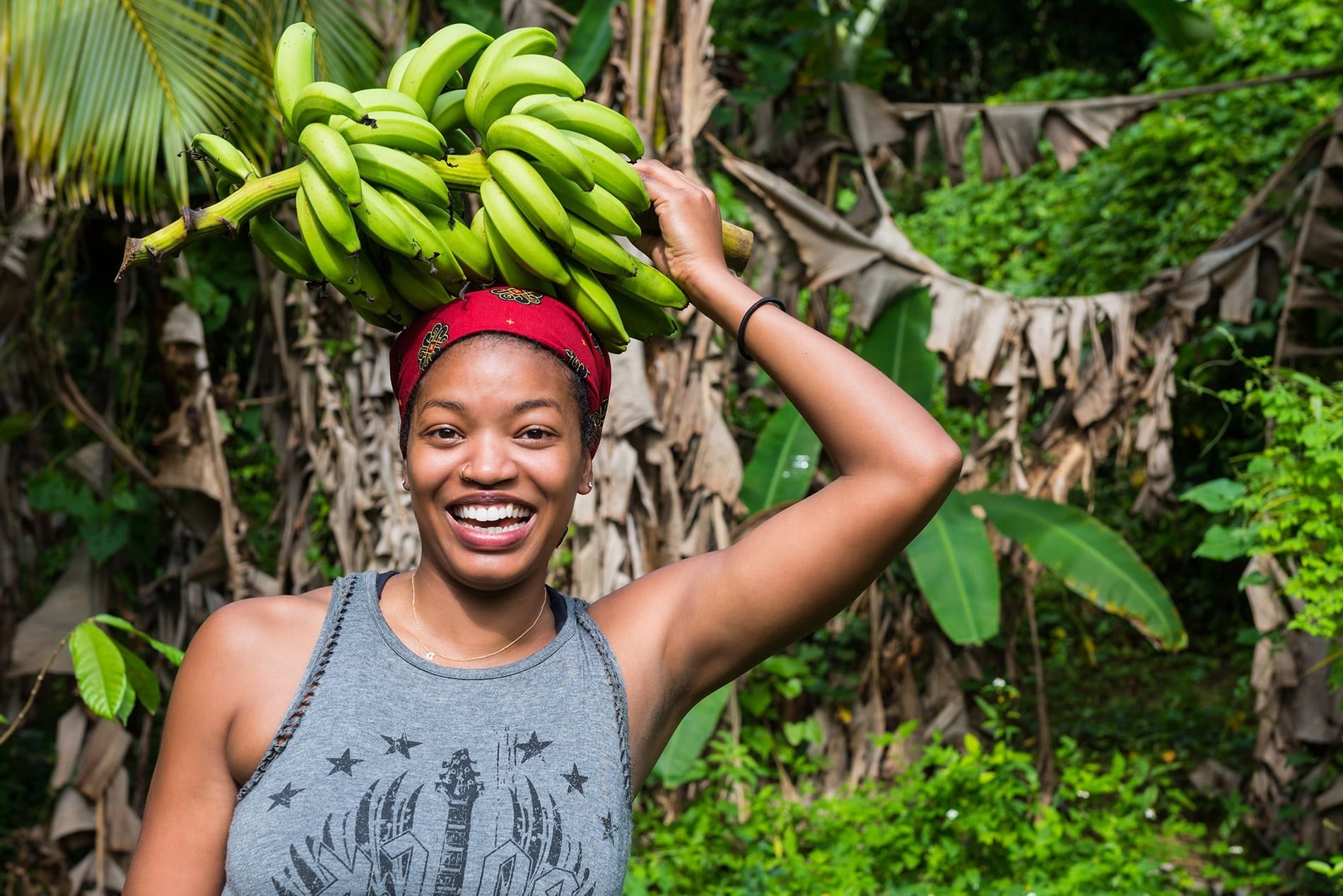 Photo Femme metisse souriante avec régime de banane posé sur la tête